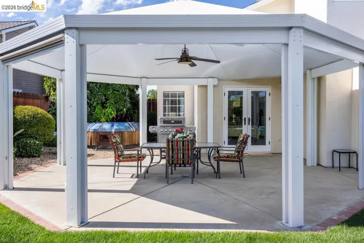Covered patio featuring a ceiling fan, concrete flooring, and direct access to the interior via French doors