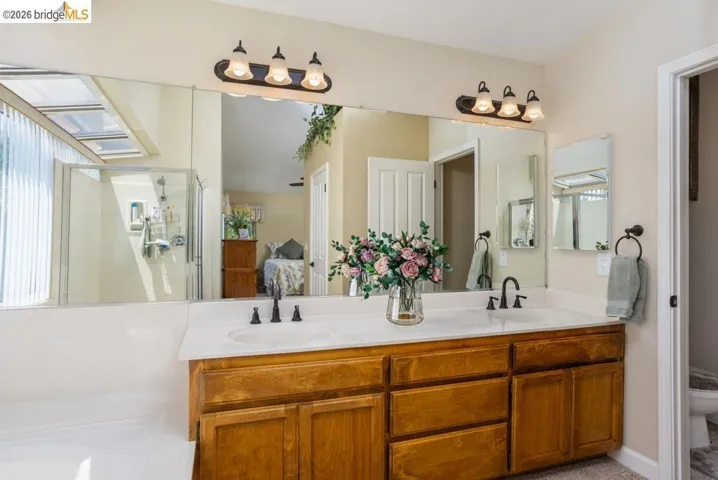 Dual vanity featuring wood cabinetry, white countertops, and matte black fixtures