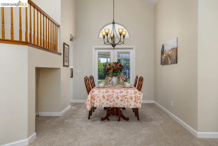 Dining area featuring a vaulted ceiling and an arched window above double glass doors