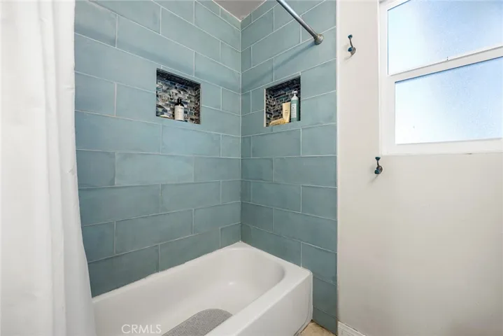 Shower/tub ccombo with teal tiles.