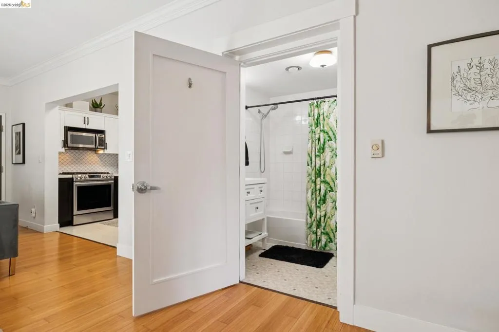 White paneled interior door opening to a bathroom with a white subway tile shower and white vanity