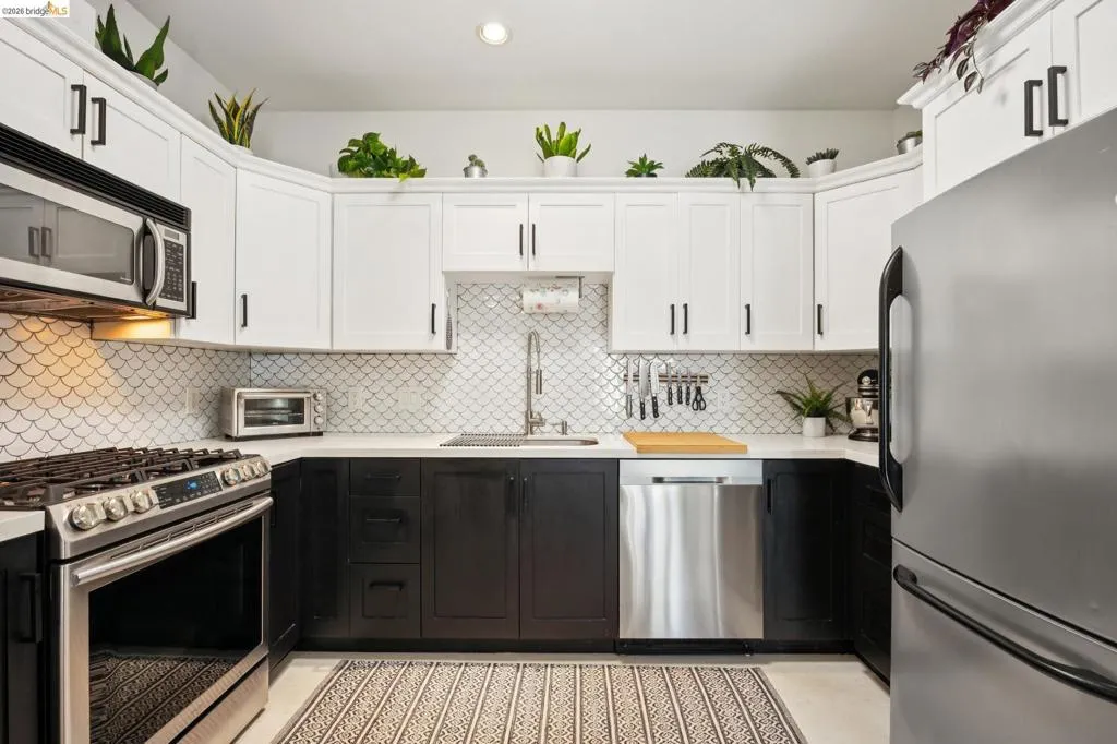 Modern kitchen featuring two-tone cabinetry with white upper and dark lower units