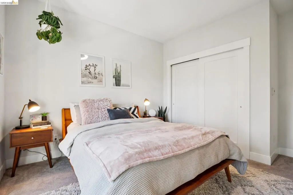 Bedroom featuring light-toned walls, plush carpeting, and a built-in closet with sliding panel doors