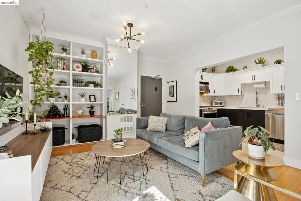 Open-concept living area featuring hardwood flooring, built-in shelving with a wood-finish counter, and a modern ceiling light fixture