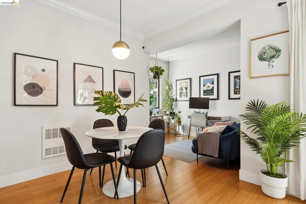 Open-concept living area featuring wood-finish flooring, a contemporary spherical pendant light, and a white crown molding trim
