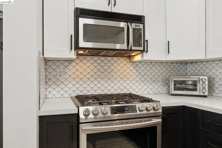 Stainless steel range with an overhead microwave, complemented by white upper cabinetry and dark lower cabinetry