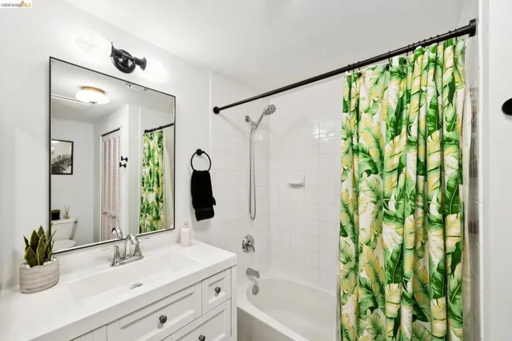 Bathroom featuring a white vanity with integrated sink, chrome faucet, and a large rectangular mirror