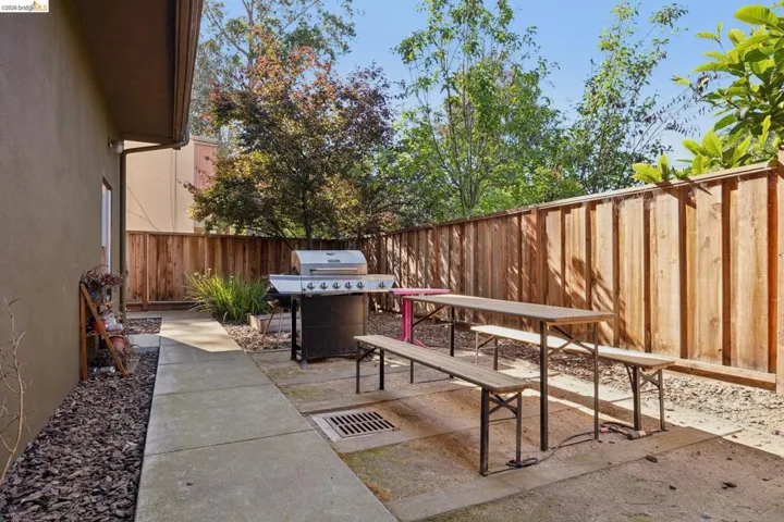 Private outdoor patio featuring concrete pavers, a wooden privacy fence, mature trees, and landscaping