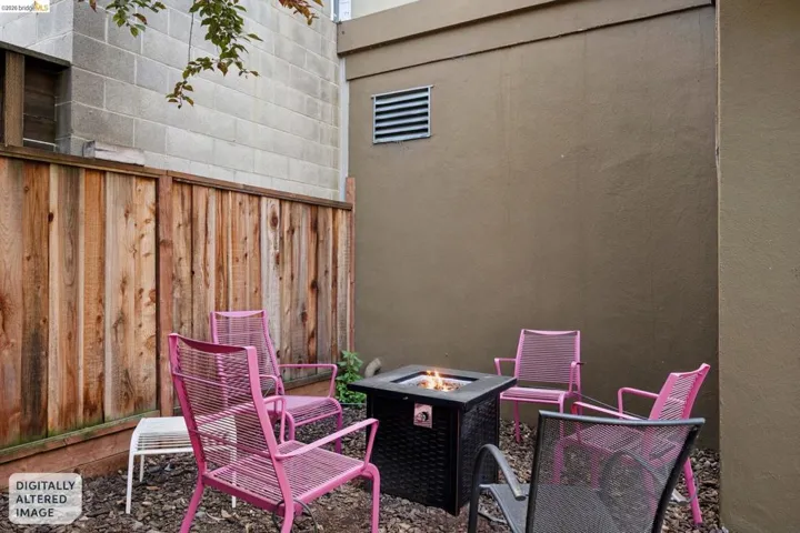 Private exterior patio featuring a wood privacy fence, stone aggregate ground cover, and a built-in fire pit