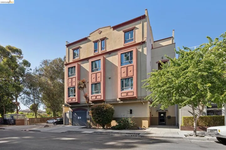 Multi-story building featuring stucco exterior, prominent bay windows, and a ground-level garage door