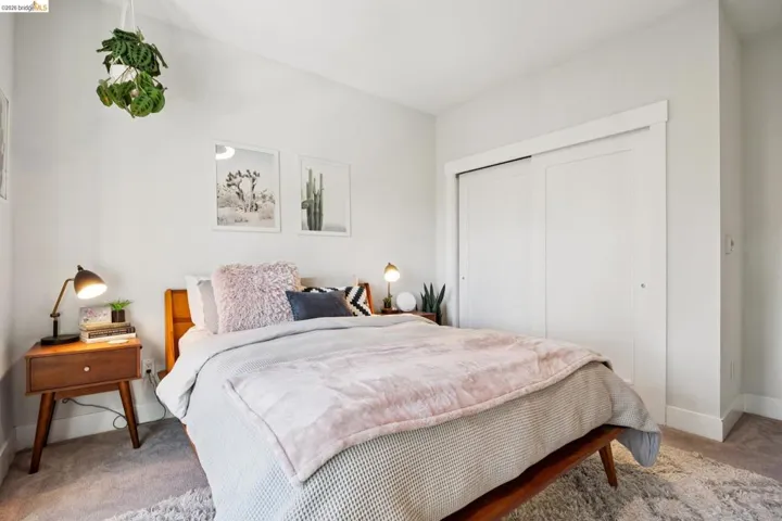 Bedroom featuring light-toned walls, plush carpeting, and a built-in closet with sliding panel doors