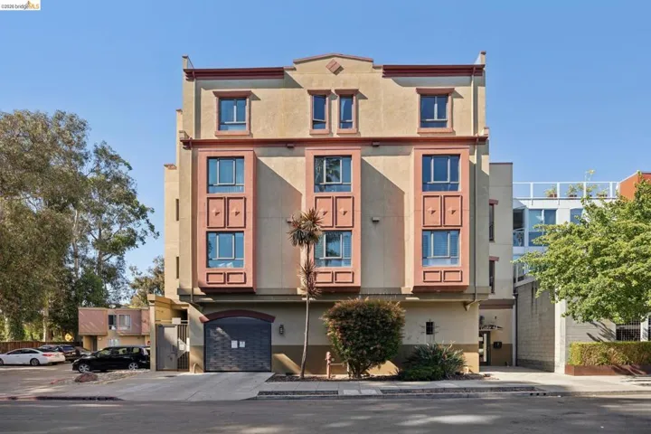 Multi-level stucco facade building featuring three prominent bay windows with multi-pane glass
