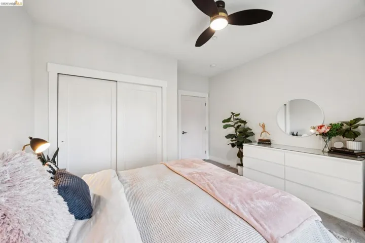 Bedroom featuring light grey walls, a ceiling fan with integrated lighting, and white sliding closet doors