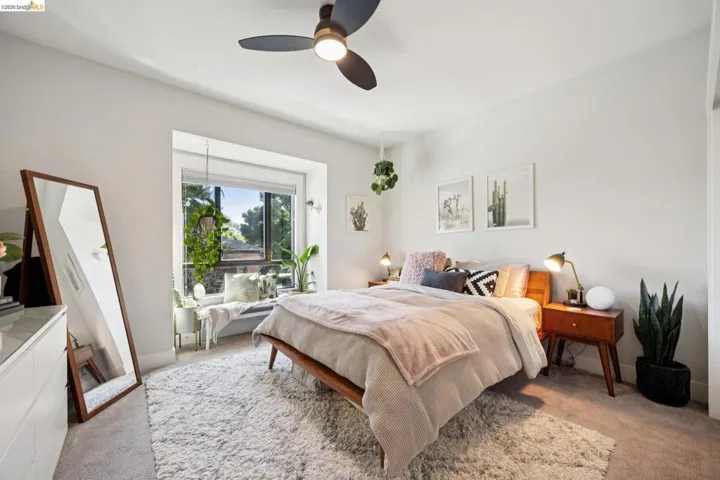 Spacious room featuring a large window with a built-in window seat, a contemporary ceiling fan with integrated lighting, and light-colored carpeting