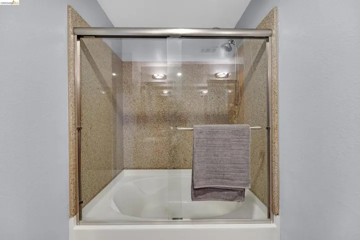 Tub-shower combination featuring a frameless glass enclosure with a towel bar