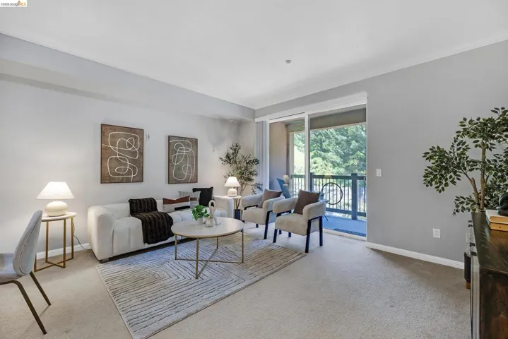Spacious living area featuring light-colored carpeting and a sliding glass door opening to an outdoor balcony
