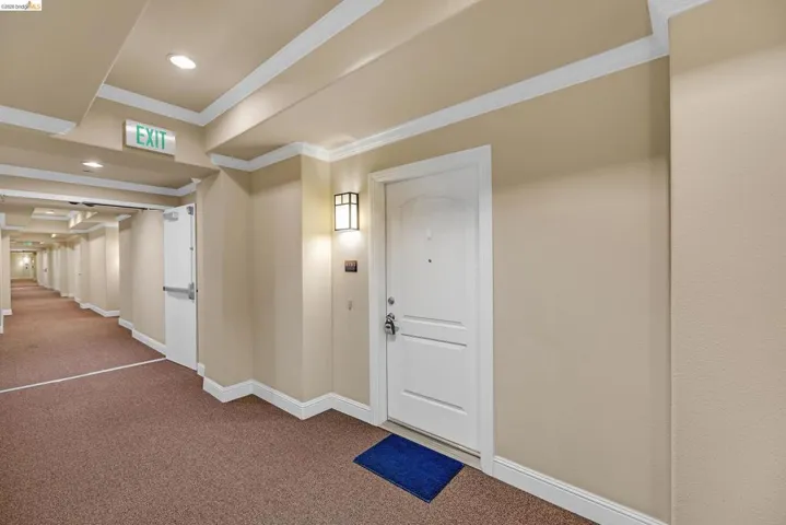 Corridor featuring an arched panel entry door, recessed ceiling lighting, a wall-mounted sconce, crown molding, and baseboards