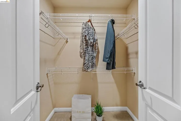 Walk-in closet featuring white wire shelving and hanging rods