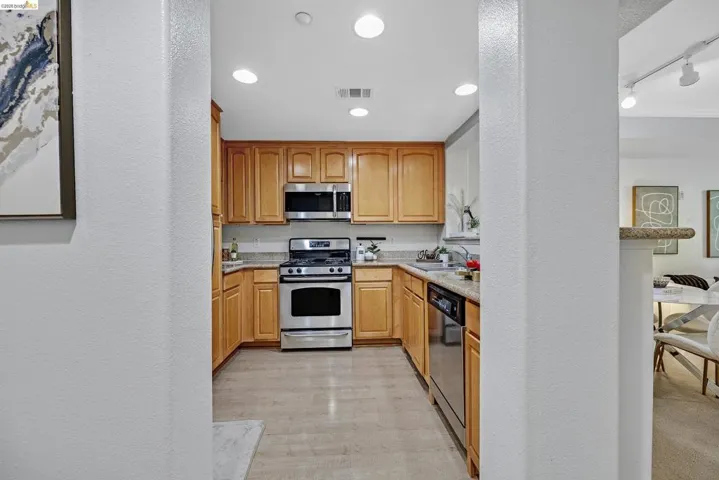 Kitchen featuring wood-finish cabinetry, light-toned countertops, and stainless steel appliances