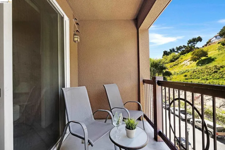Balcony featuring a sliding glass door, textured stucco exterior, and black metal railing with decorative scrollwork
