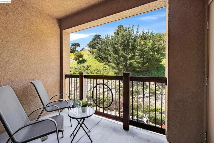 Private balcony featuring stucco walls and a wood-finish railing with black metal balusters