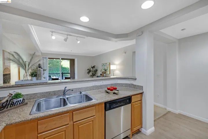 Kitchen featuring a double basin stainless steel sink, a stainless steel dishwasher, light wood cabinetry, and a granite-finish countertop