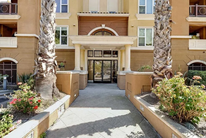 Stucco exterior featuring a grand entrance with fluted columns, a decorative arched transom, and double glass entry doors