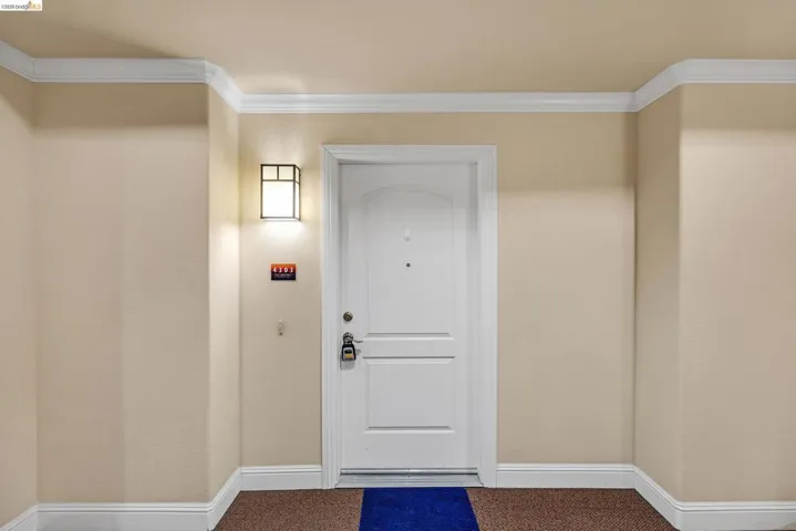 Entryway featuring a white paneled door with an arched top panel and a transom-style wall sconce