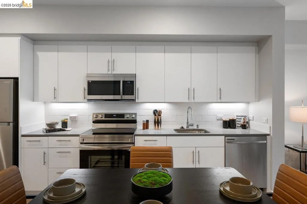 Kitchen featuring stainless steel appliances, white cabinets, and decorative backsplash