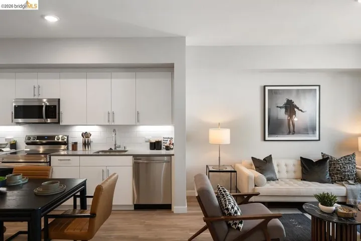Kitchen with stainless steel appliances, light wood finished floors, white cabinets, decorative backsplash, and modern cabinets