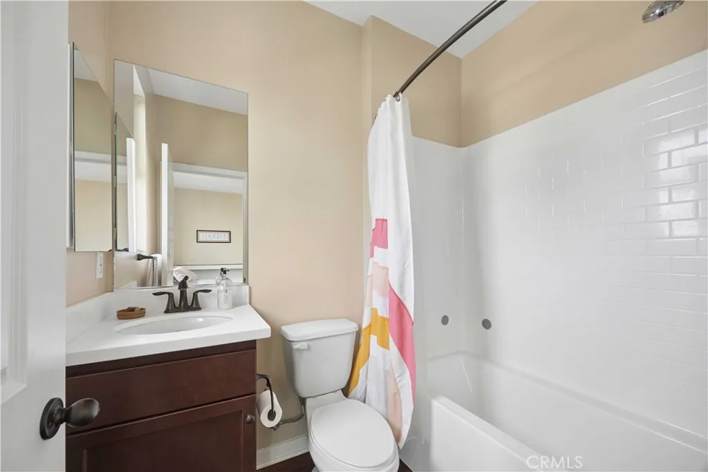 Full en-suite bathroom featuring tub/shower combo and matching dark vanity cabinetry.