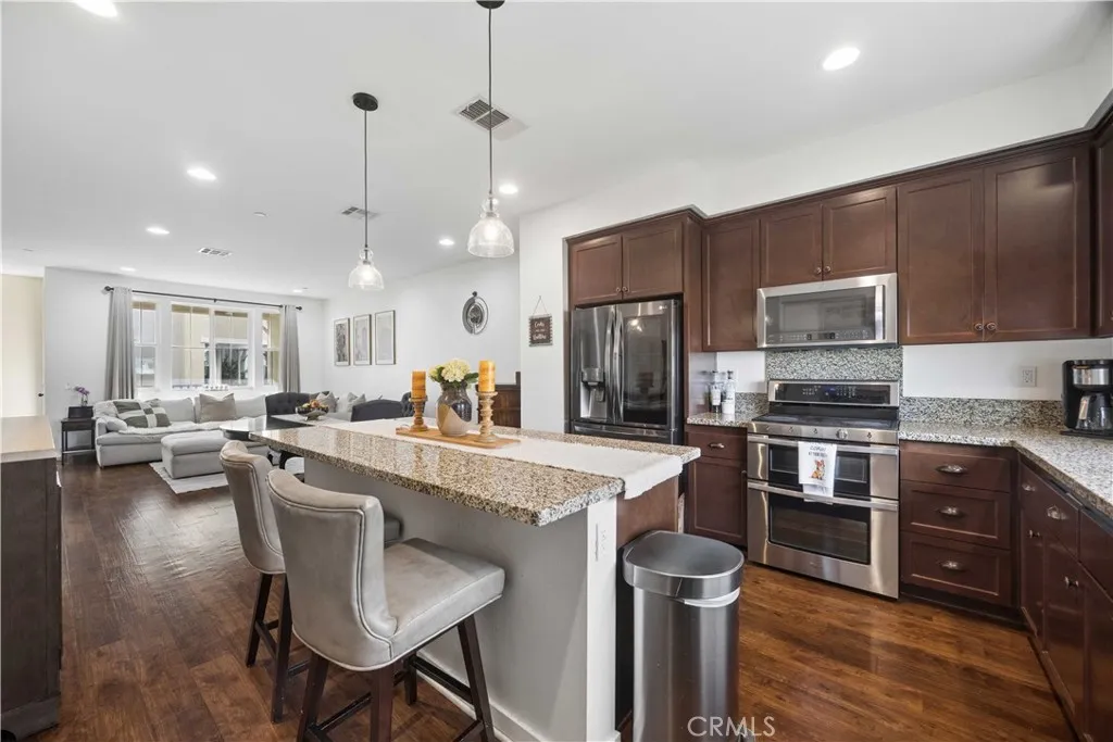 Gourmet kitchen flows seamlessly into the open-concept living area with a granite island, stainless steel appliances & designer pendant lighting