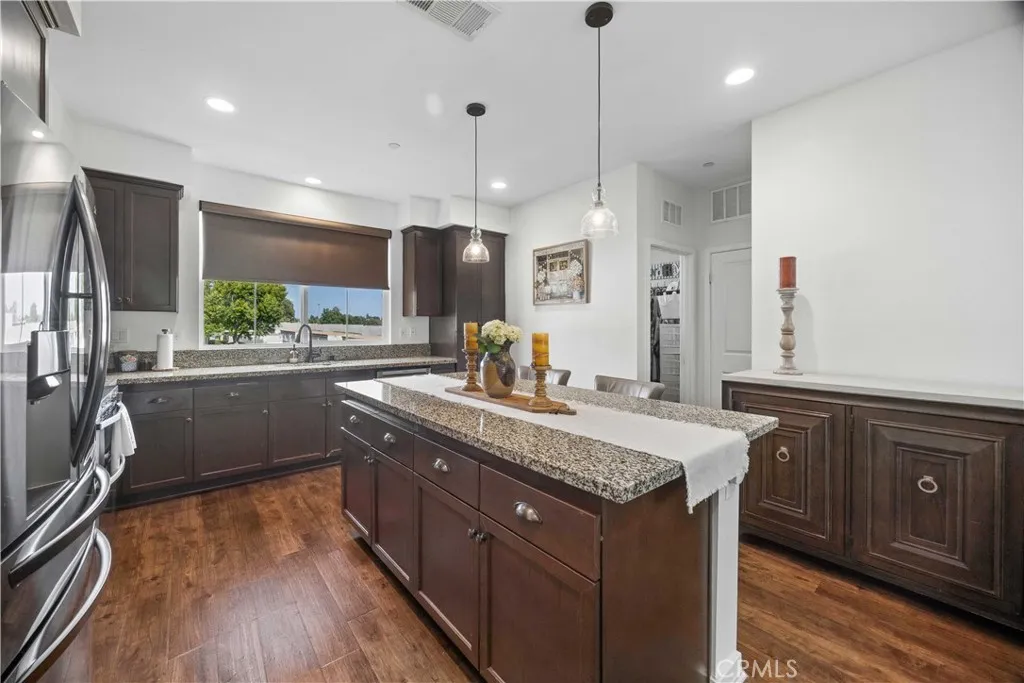 Spacious kitchen with large center island, granite counters, espresso shaker cabinetry, pendant lighting & breakfast bar seating.