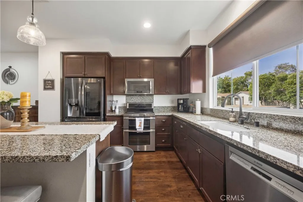 Chef's kitchen featuring granite countertops, rich espresso cabinetry, double oven, stainless appliances & garden window with natural light.