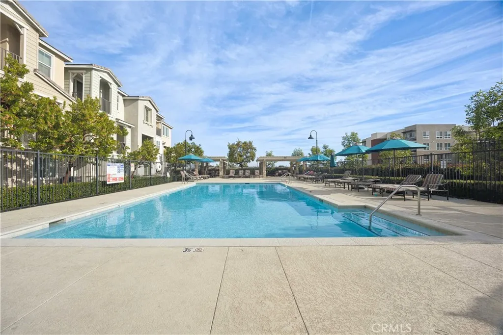 Resort-style community pool with lounge seating, shade umbrellas & stunning open sky views.