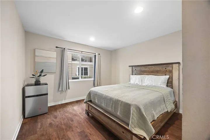 Entry-level bedroom with natural light & rustic wood bed frame, versatile space for guests or a home office.