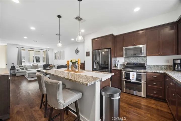 Gourmet kitchen flows seamlessly into the open-concept living area with a granite island, stainless steel appliances & designer pendant lighting