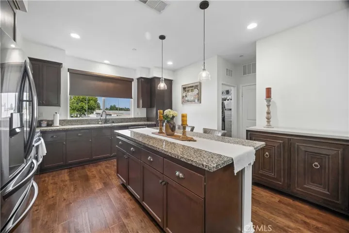 Spacious kitchen with large center island, granite counters, espresso shaker cabinetry, pendant lighting & breakfast bar seating.