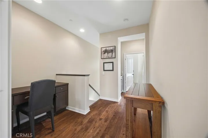 Third-floor hallway landing featuring built-in desk, rich hardwood flooring, and recessed lighting. perfect for a home office or study space.
