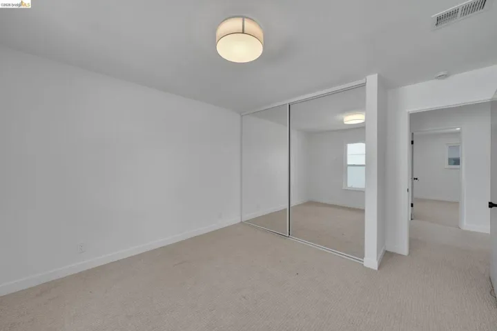 Bedroom featuring mirrored closet doors, recessed ceiling light, white walls, and neutral carpeting