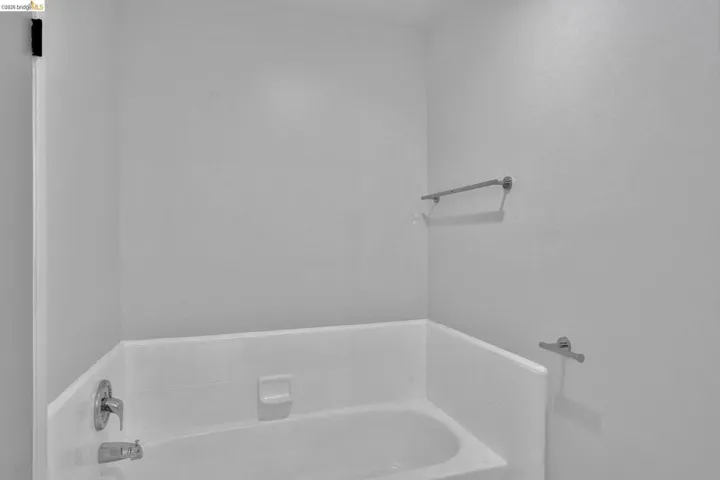 White bathtub with chrome fixtures, integrated soap dish, and tile surround