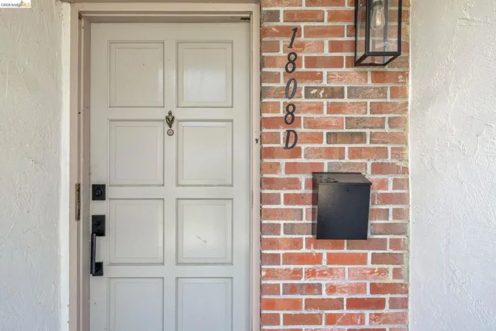 Panel door entrance featuring a contemporary matte black handle set, a coordinating wall-mounted mailbox, and a geometric exterior light fixture
