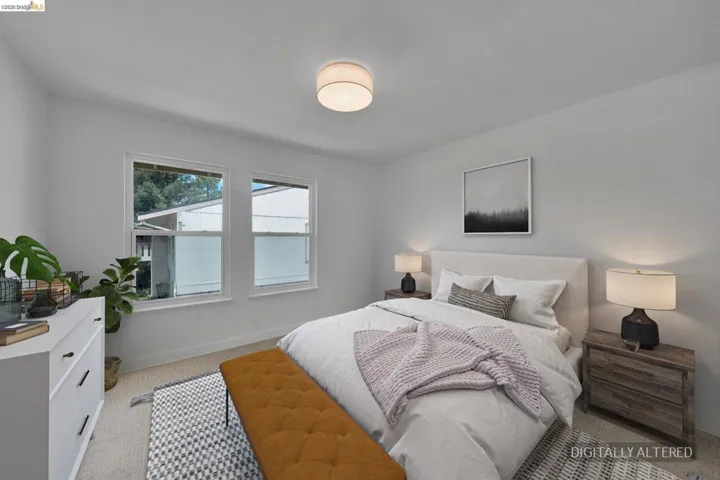 Bright bedroom featuring two large windows, white walls, light-toned flooring, and a flush mount ceiling light