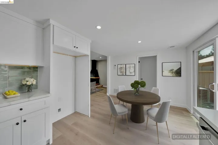 Bright kitchen and dining area featuring white cabinetry, light wood-finish flooring, a teal subway tile backsplash, and a large sliding glass door