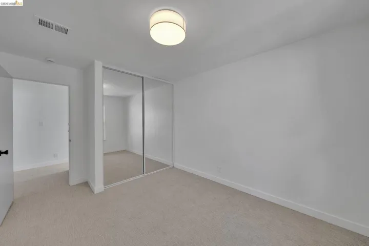 Bedroom featuring wall-to-wall carpeting, mirrored closet doors, a flush-mount ceiling light fixture, and white painted walls