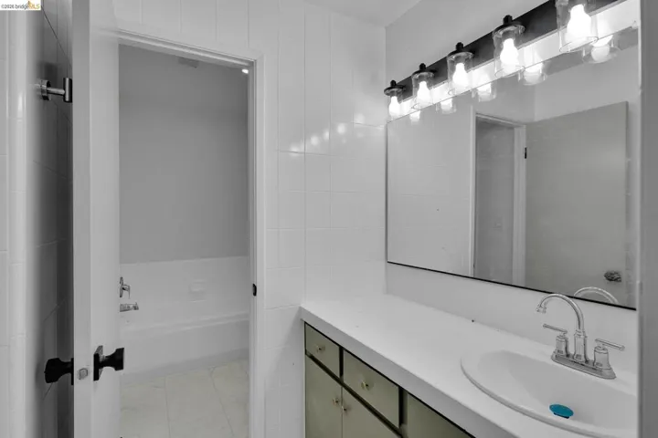 Bathroom featuring a white vanity with an integrated sink, a large wall-mounted mirror, and a five-light vanity fixture