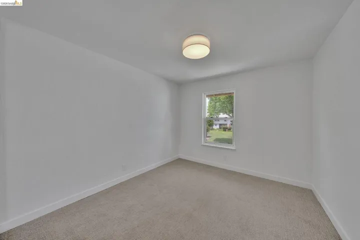 Neutral wall color with a single window and flush-mount ceiling light
