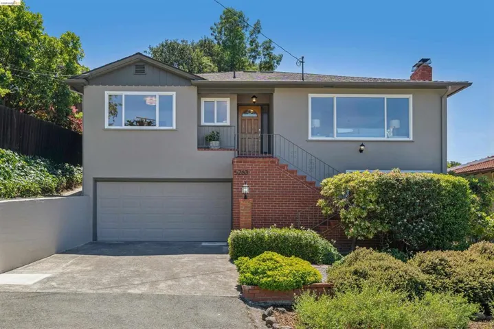 Contemporary stucco exterior featuring a large picture window, brick staircase, and an integrated garage