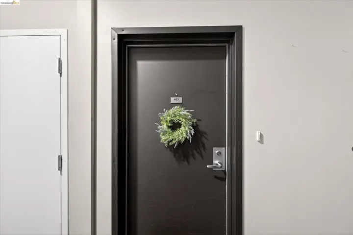 Dark-toned entry door with a door number plaque and silver-toned hardware