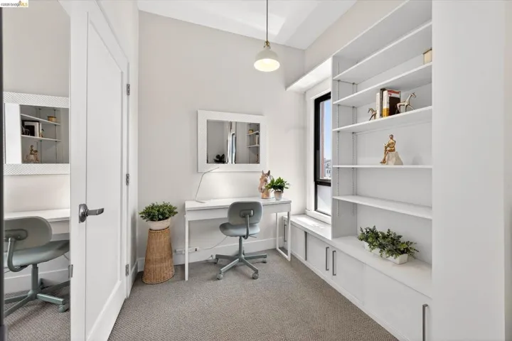 Dedicated office space featuring built-in shelving, integrated lower cabinetry, a window seat, and neutral-toned carpeting